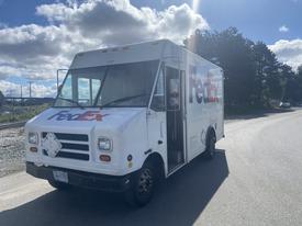 A white 1999 Ford Econoline delivery truck with the FedEx logo on the side parked on a street