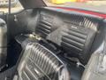 Interior of a 1966 Ford Mustang showing the back seat with black leather upholstery featuring vertical stitching and seat belts