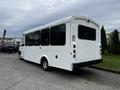 A 2017 Chevrolet Express bus with a white exterior and large tinted windows parked in a lot