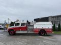 A red and white 2001 Freightliner FL80 fire truck with a water tank and equipment compartments mounted in the rear and lights on top