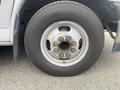 A close-up of the front wheel of a 2017 Chevrolet Express showing a silver rim with eight lug nuts and a tire marked with size and brand information