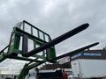 A 2003 John Deere 790 tractor with a green front loader attachment and two long black forks positioned horizontally