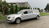 A silver 2013 Lincoln MKT hearse parked on a street with a distinctive elongated body and a raised exterior cover