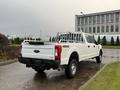 A white 2017 Ford F-350 Super Duty pickup truck with a metal bed rack parked on a wet surface