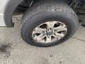 A close-up of a dirty tire and wheel from a 2014 Ford F-150 with a silver alloy rim and rugged tread visible