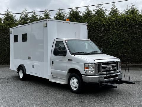 A silver 2013 Ford Econoline with a large white cargo area and a front-mounted hitch attachment