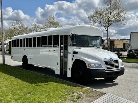 A 2022 Blue Bird BB Conventional bus with a white exterior and large windows parked on the side of a road