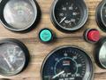 Close-up of dashboard dials and gauges from a 1991 Western Star 3800 showing speedometer oil pressure gauge and other indicators with a green button in the center