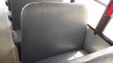 A gray bus seat with a padded backrest in the foreground