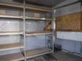 Interior of a 2010 Forest River Enclosed trailer featuring metal shelving units and wooden shelves along the walls