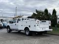 A white 2013 Ford F-350 SD truck with a utility bed and various equipment mounted in the rear