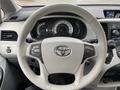 A 2013 Toyota Sienna steering wheel with controls for audio and cruise settings featuring the Toyota emblem in the center