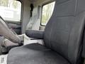 The interior of a 2014 Kenworth T370 truck showing the driver's seat and armrest with black fabric upholstery and a grey console