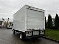 A 2012 Mitsubishi Fuso FE box truck with a white exterior and a rear loading area featuring red and white reflective markers