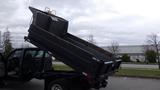 A 2008 Ford F-450 SD truck with its dump bed raised, showing an open metal container designed for transporting materials