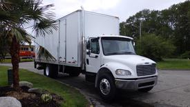 A white 2016 Freightliner M2 106 box truck with a tall cargo area and a chrome grille parked on a paved area