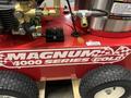 2024 Magnum 4000 Hot Water Pressure Washer featuring a red body with the text Magnum 4000 Series Gold and equipped with various hoses and attachments on the side