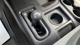 Close-up of a manual gear shifter in a 2013 RAM 2500 with a textured black grip and adjacent cup holders