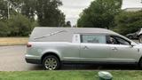 A silver 2013 Lincoln MKT hearse with a gray top and distinctive features designed for transporting caskets