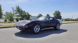 A 1971 Chevrolet Corvette Stingray in dark purple with a sleek design and chrome accents sitting in a parking lot