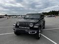 A black 2019 Jeep Wrangler stands in an empty parking lot with a distinctive front grille and round headlights