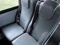 Two gray upholstered seats with seat belts in a vehicle cabin