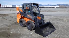 A 2017 Gehl R105 Skid Steer Loader with an orange and black color scheme has a bucket attachment in the front and four wheels visible