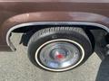 The image shows the wheel of a 1982 Mercury Grand Marquis featuring a chrome hubcap and a black tire with whitewall detailing