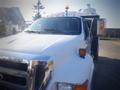 A white 2006 Ford F-650 with a prominent grille and headlights is shown from a front angle with a visible side mirror and a yellow light on the roof