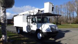 A white 2008 International 4300 bucket truck with a Terex aerial lift mounted on the back and a storage compartment on the side