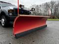 A 2009 Ford F-550 truck equipped with a large red snow plow mounted at the front