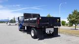 A blue 2012 International DuraStar 4300 truck with a black dump bed parked in a lot