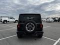 A black 2019 Jeep Wrangler with a large spare tire mounted on the rear and a distinctive seven-slot grille