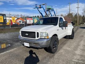 A white 2000 Ford F-350 SD with a black grill and rims parked on a road