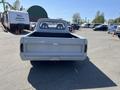 A rear view of a 1962 Ford F-100 pickup truck with a light gray finish and the word "FORD" emblazoned across the tailgate
