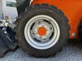 Close-up of a tire from a 2017 Gehl R105 featuring a heavy tread design and steel rim with visible bolts and an orange hub