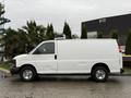 A white 2009 Chevrolet Express van with a refrigeration unit on the roof parked on a flat surface