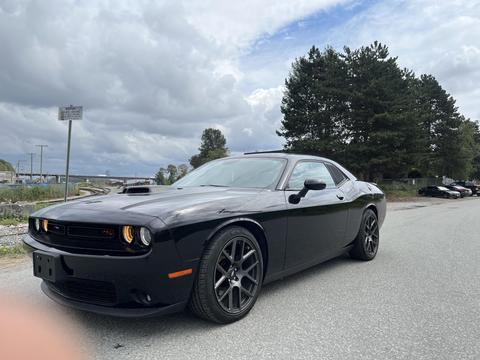 A black 2017 Dodge Challenger with a sleek design and sporty wheels parked on a gravel surface