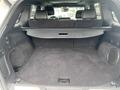 The interior of a 2018 Jeep Grand Cherokee with an empty cargo area featuring a retractable cover and black carpeted floor