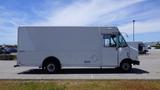 A 2011 Ford Econoline van in white with a boxy shape and a sliding side door parked in a lot