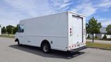 A white 2011 Ford Econoline cargo van with a boxy shape and rear access door parked on a road