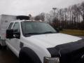 A 2009 Ford F-450 SD with a white body and black accents featuring a roof-mounted spotlight and amber clearance lights on top of the cab