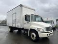 A white 2008 Hino Conventional Cab truck with a large box cargo area and graffiti on the side, positioned in a fleet of similar vehicles