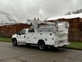 2004 Ford F-450 SD utility truck with a white body and an elevated bucket lift mounted on the back designed for servicing utility lines