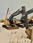 2009 John Deere 135 D excavator with a yellow and gray body a long arm and a bucket attachment on its front tracks in a snowy area