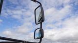 A close-up of the side mirrors of a 2015 International PC105 truck reflecting the sky and clouds