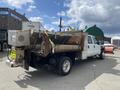A 2010 Ford F-550 truck with a flatbed and mounted equipment in the rear half featuring a wooden structure and a metal hopper