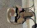 A rusted round cover with a metal housing and connected wires sits on a metal grate