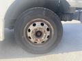 A close-up view of a wheel from a 1999 Ford Econoline van showing a steel rim with multiple holes and a worn tire