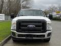 Front view of a 2011 Ford F-250 SD with a black grille and chrome accents showcasing its large headlights and wide bumper